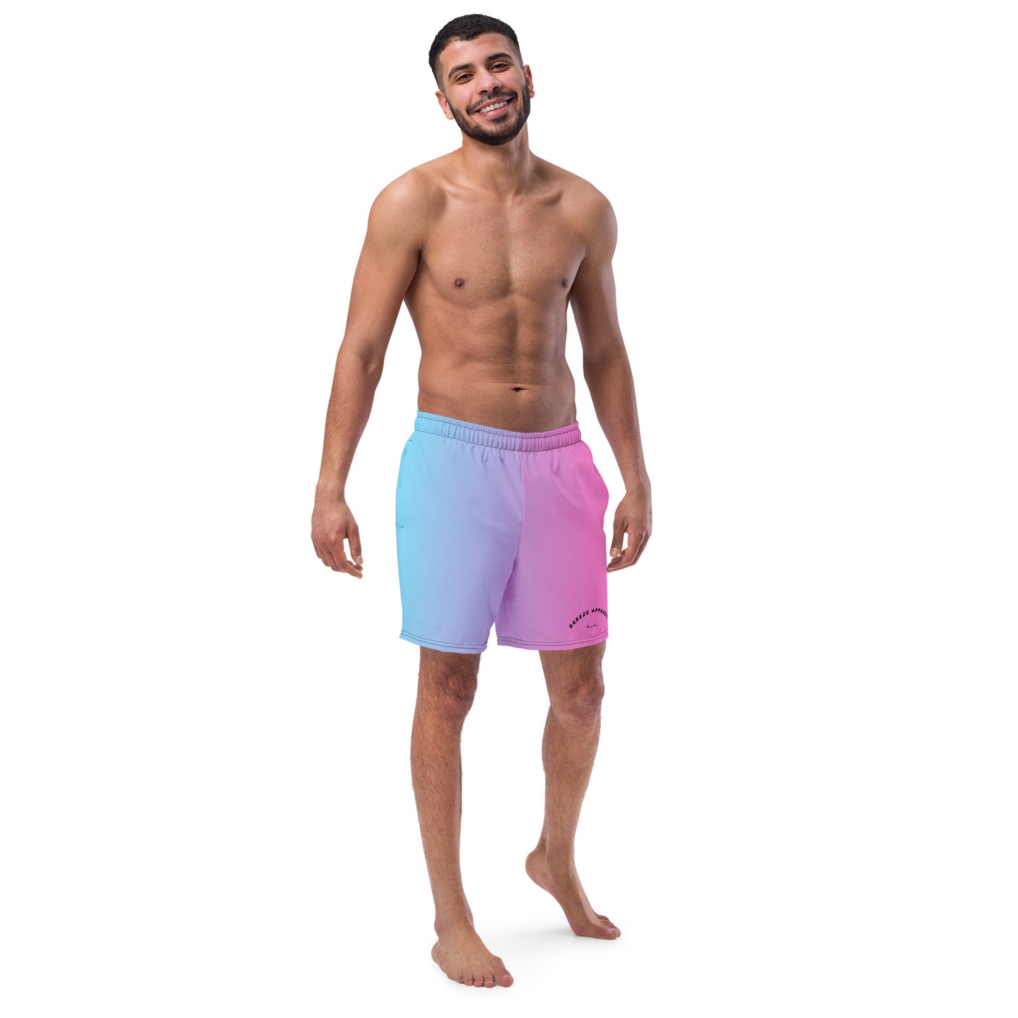 Man wearing swim trunks with a light-blue-to-pink design and a black 'Breeze Apparel Miami' word logo on the bottom-left knee