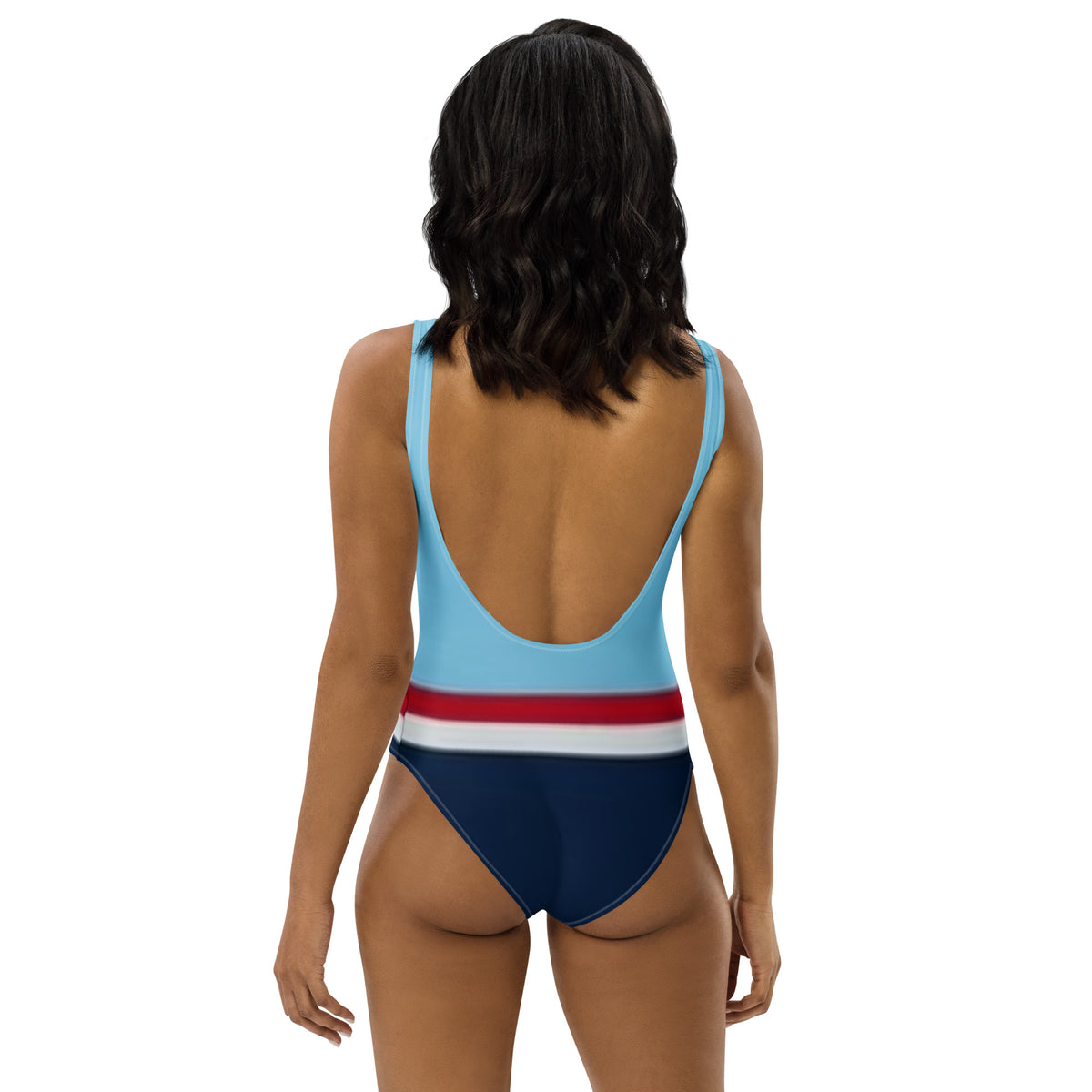 Rear view of woman wearing one-piece swimsuit with light-blue top, followed by a red stripe, then a white stripe, followed by a navy-blue bottom part.