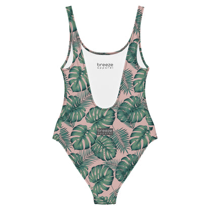 Back of one-piece swimsuit with a design of palm leaves set on a pink background.