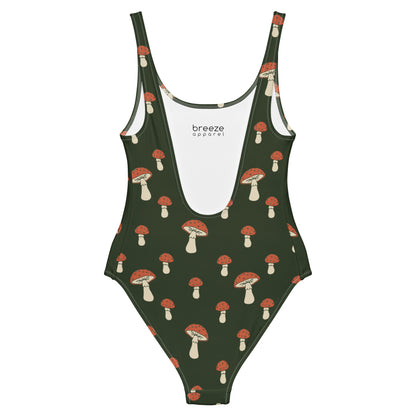 One-piece swimsuit with pattern of mushrooms set on green background.