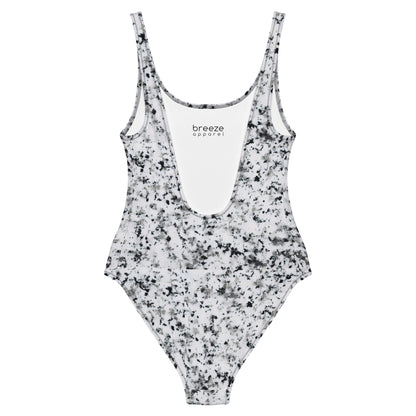 One-piece swimsuit with pattern of black splotches set on a white background.