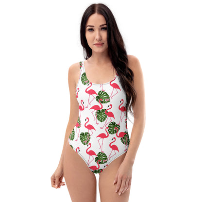 Woman wearing a white, one-piece swimsuit with a pattern consisting of flamingos and palm leaves. 