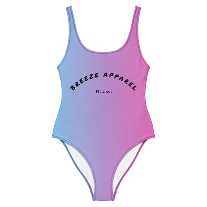 Women's one-piece swimsuit with a light-blue-to-pink design and a black 'Breeze Apparel Miami' word logo across the chest.
