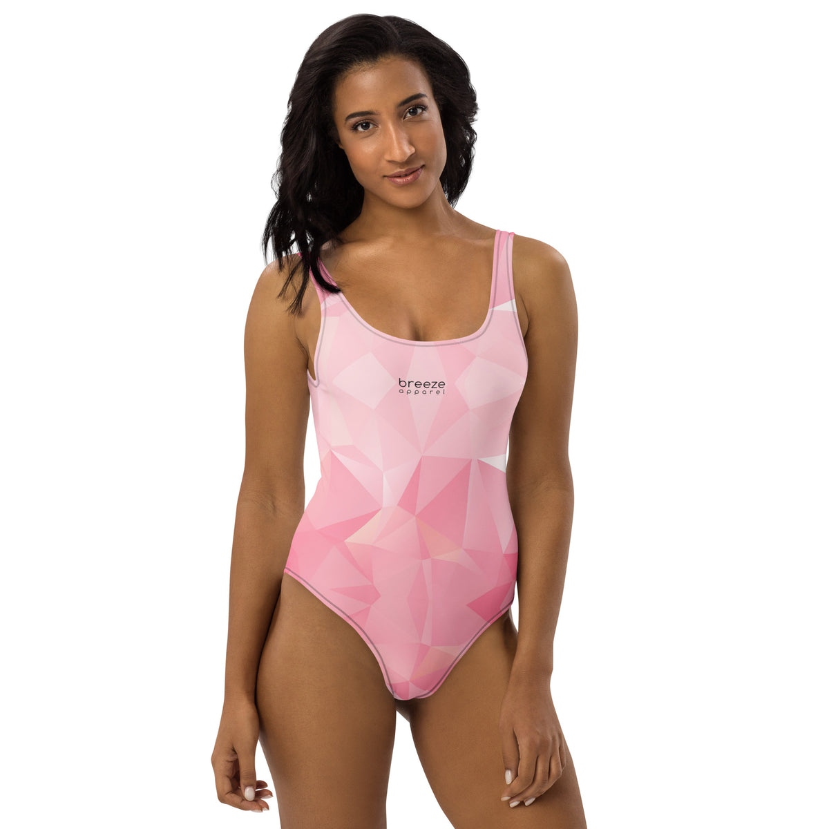 Woman wearing one-piece swimsuit with all-over, pink geometric pattern. 'Breeze apparel' is in small, black text on chest.