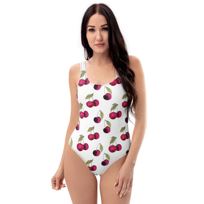 Woman wearing white, one-piece swimsuit with pattern of cherries.