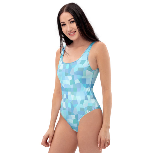 Woman wearing one-piece swimsuit with all-over, cyan geometric pattern.