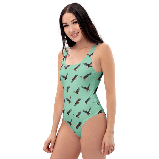 Woman wearing green one-piece swimsuit with pattern of bald eagles.