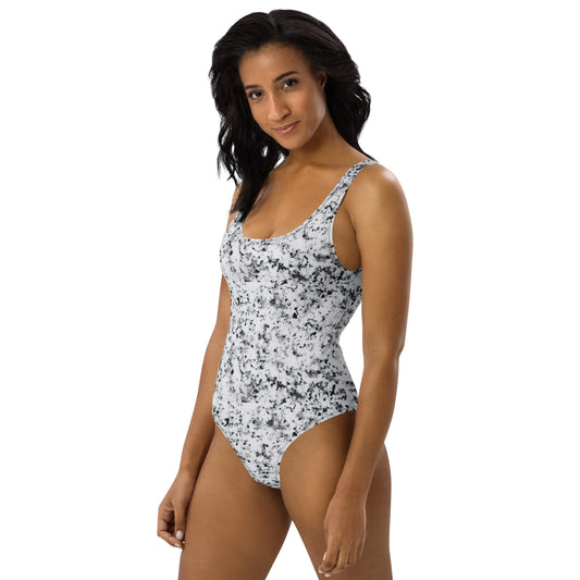 Woman wearing one-piece swimsuit with pattern of black splotches set on a white background.