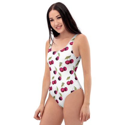 Woman wearing white, one-piece swimsuit with pattern of cherries.