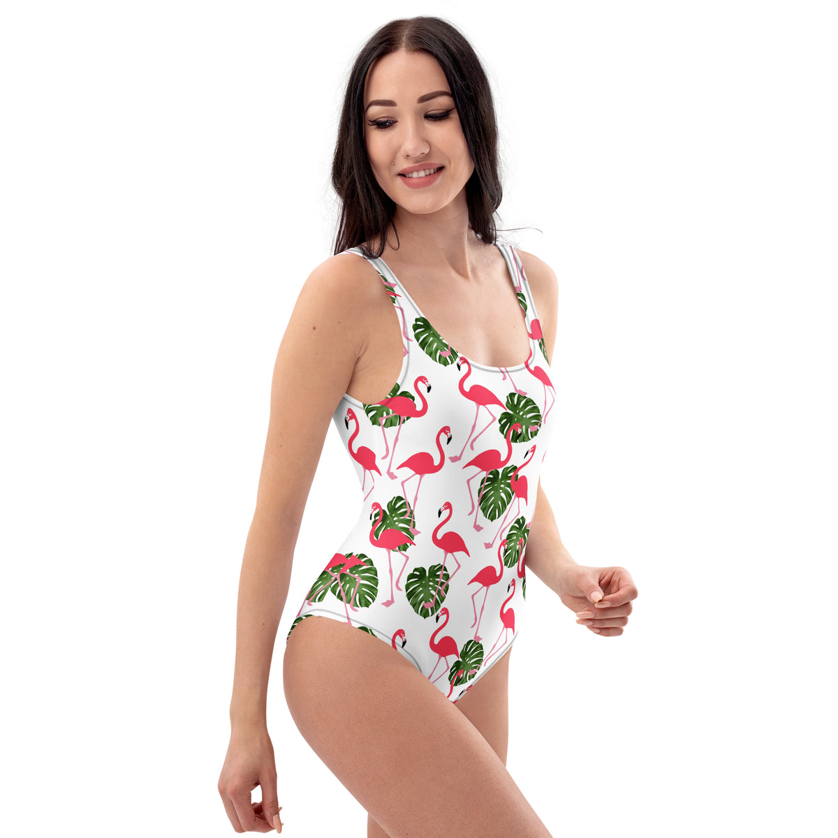 Woman wearing a white, one-piece swimsuit with a pattern consisting of flamingos and palm leaves. 