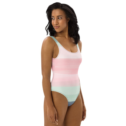 Woman wearing a one-piece swimsuit with a pink, pastel-green, and gray design that resembles watercolor.