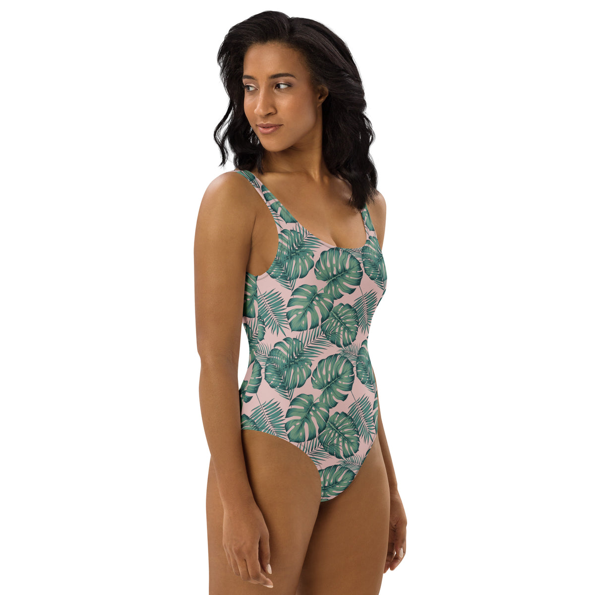Woman wearing one-piece swimsuit with a design of palm leaves set on a pink background.