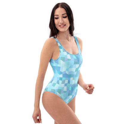 Woman wearing one-piece swimsuit with all-over, cyan geometric pattern.