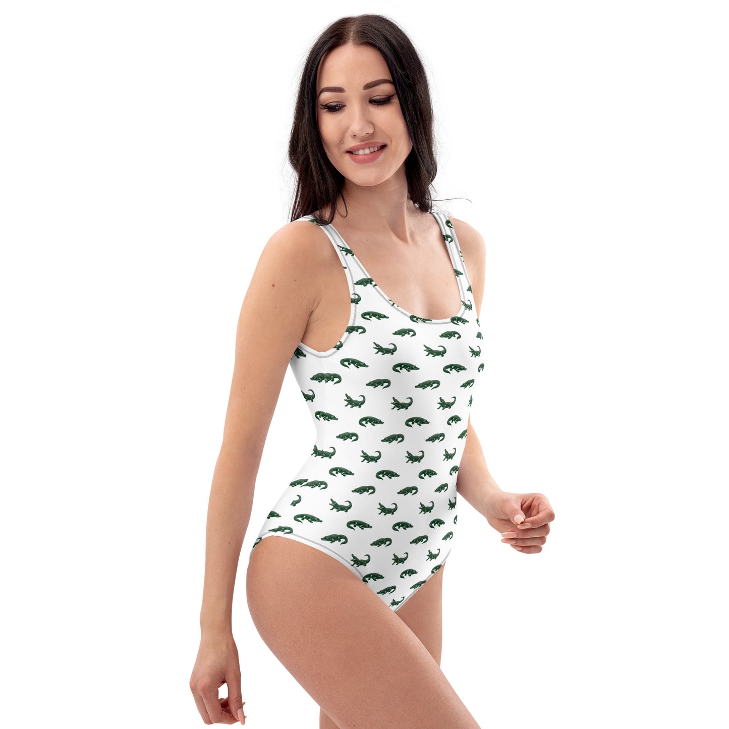 Woman wearing white one-piece swimsuit with pattern of green alligators.