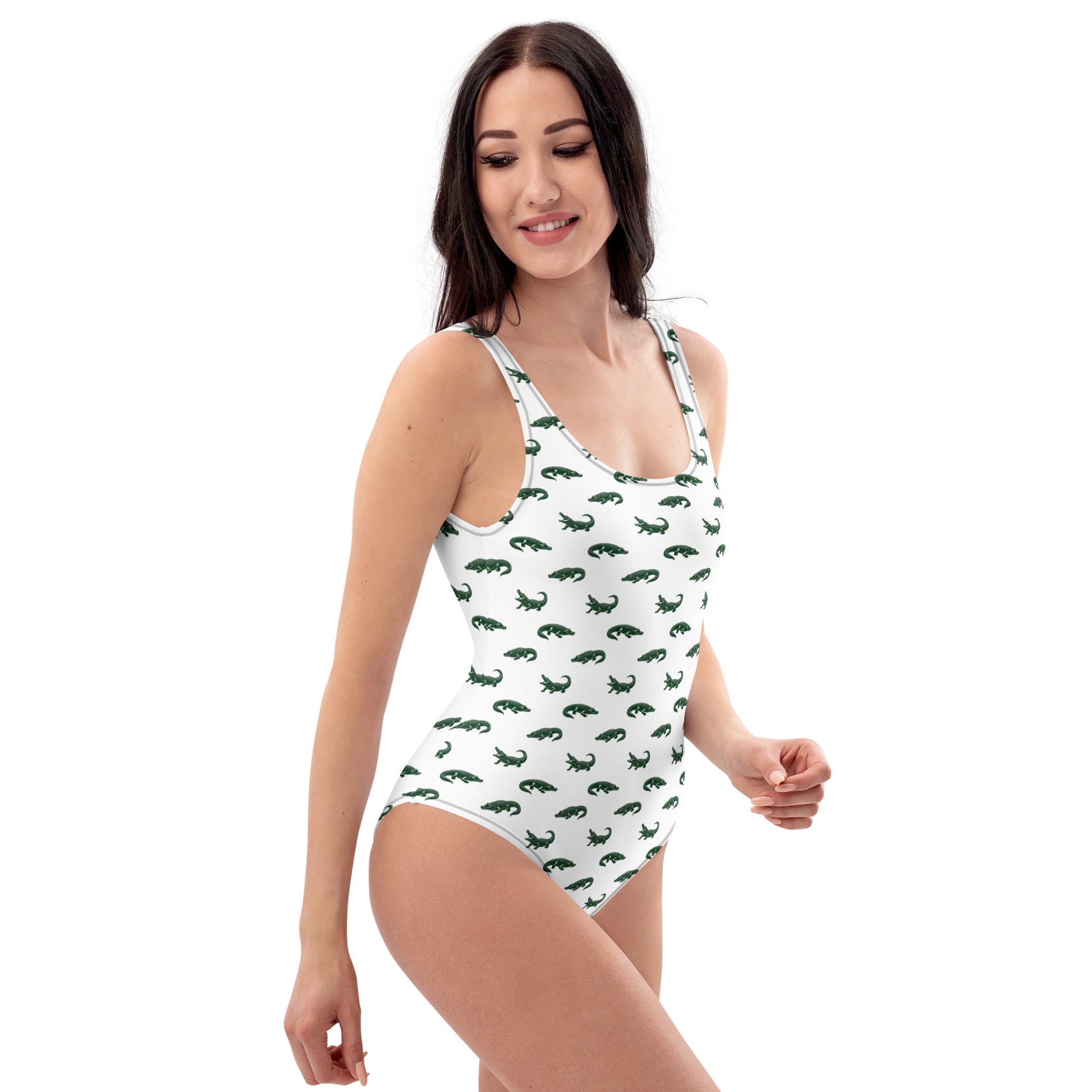 Woman wearing white one-piece swimsuit with pattern of green alligators.