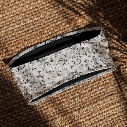 Back of bandeau bikini top that has a pattern of black splotches set on a white background, laying in sunlight.