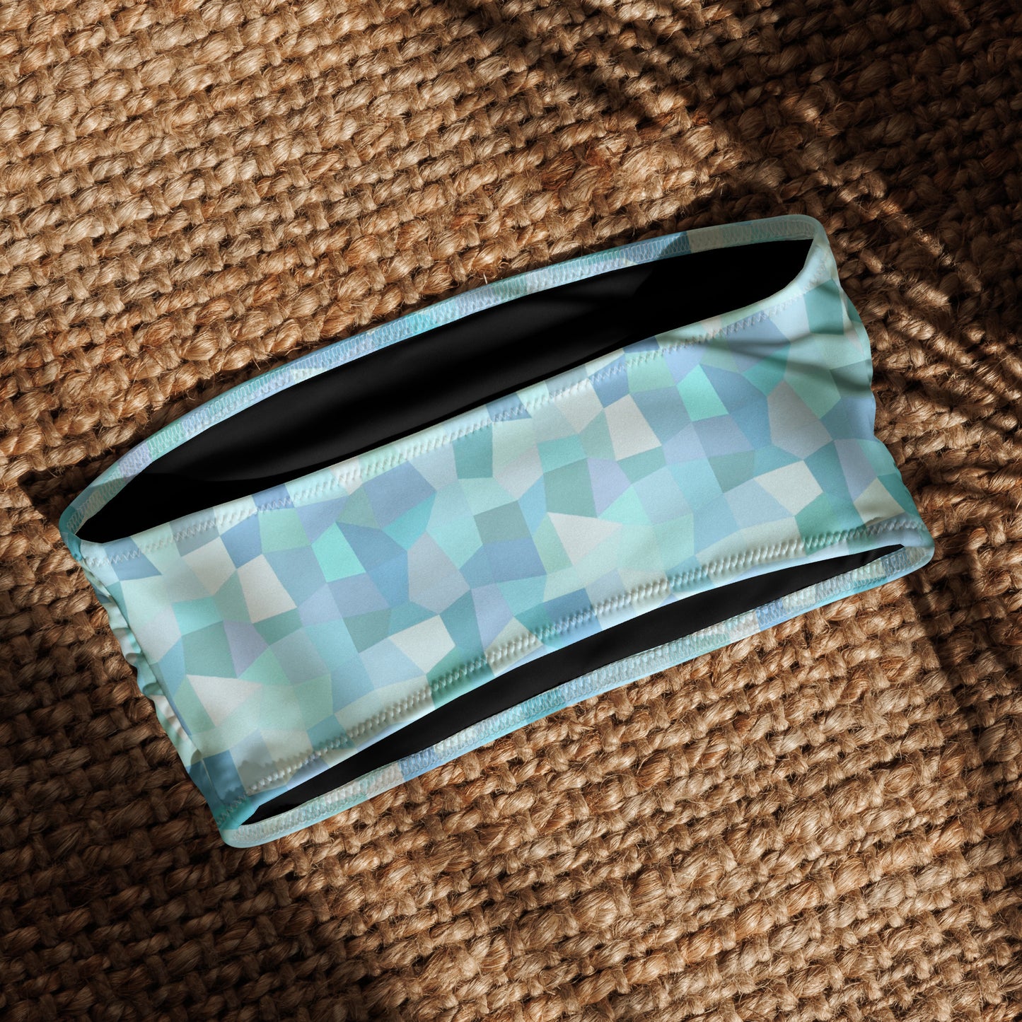 Back og bandeau bikini top with cyan geometric pattern, laying in sunlight.