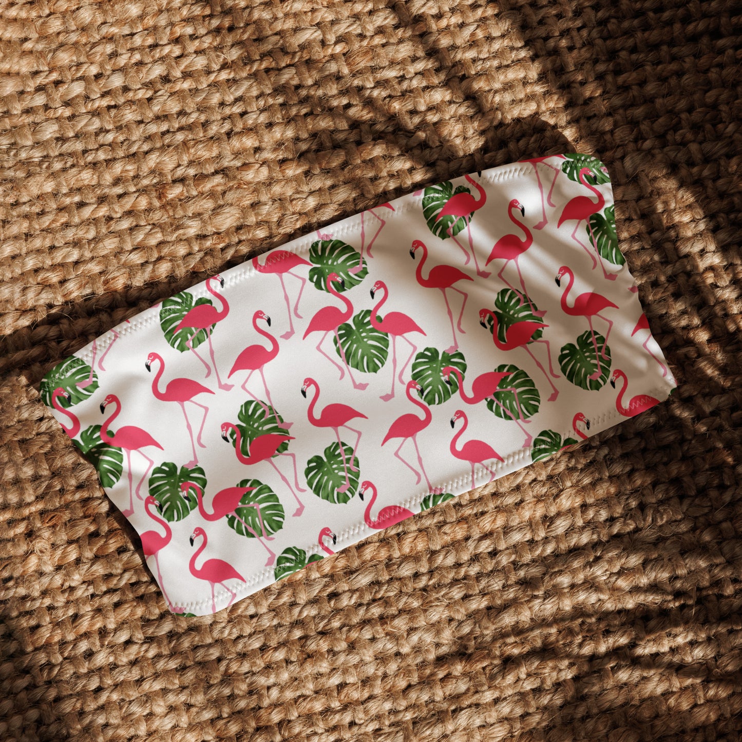 White bandeau bikini top with all-over flamingos design, laying in sunlight.