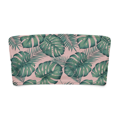 Bandeau bikini top with design of green palm leaves set on a pink background.