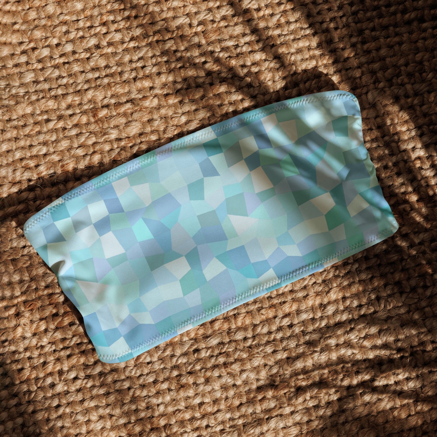Bandeau bikini top with cyan geometric pattern, laying in sunlight.