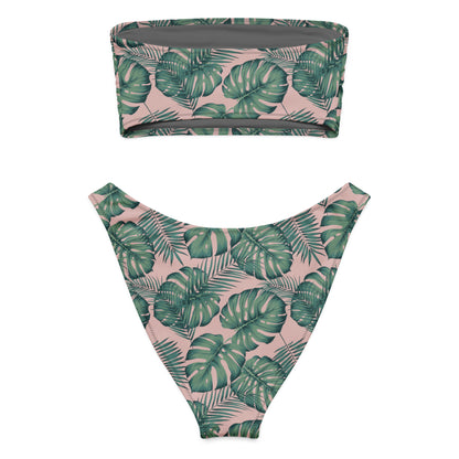 Bandeau bikini with design of green palm leaves set on a pink background.