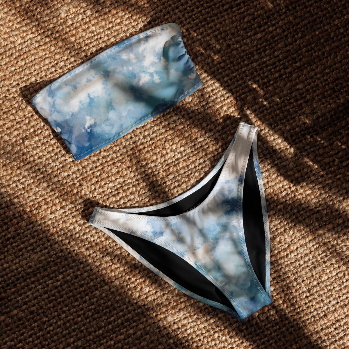 Bandeau bikini with a blue-white, watercolor-like design, laying in sunlight.