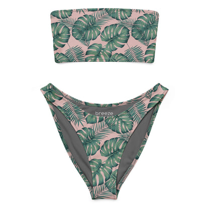 Bandeau bikini with design of green palm leaves set on a pink background.