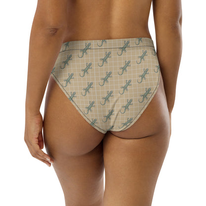 Woman wearing beige bikini bottom with pattern of green geckos.