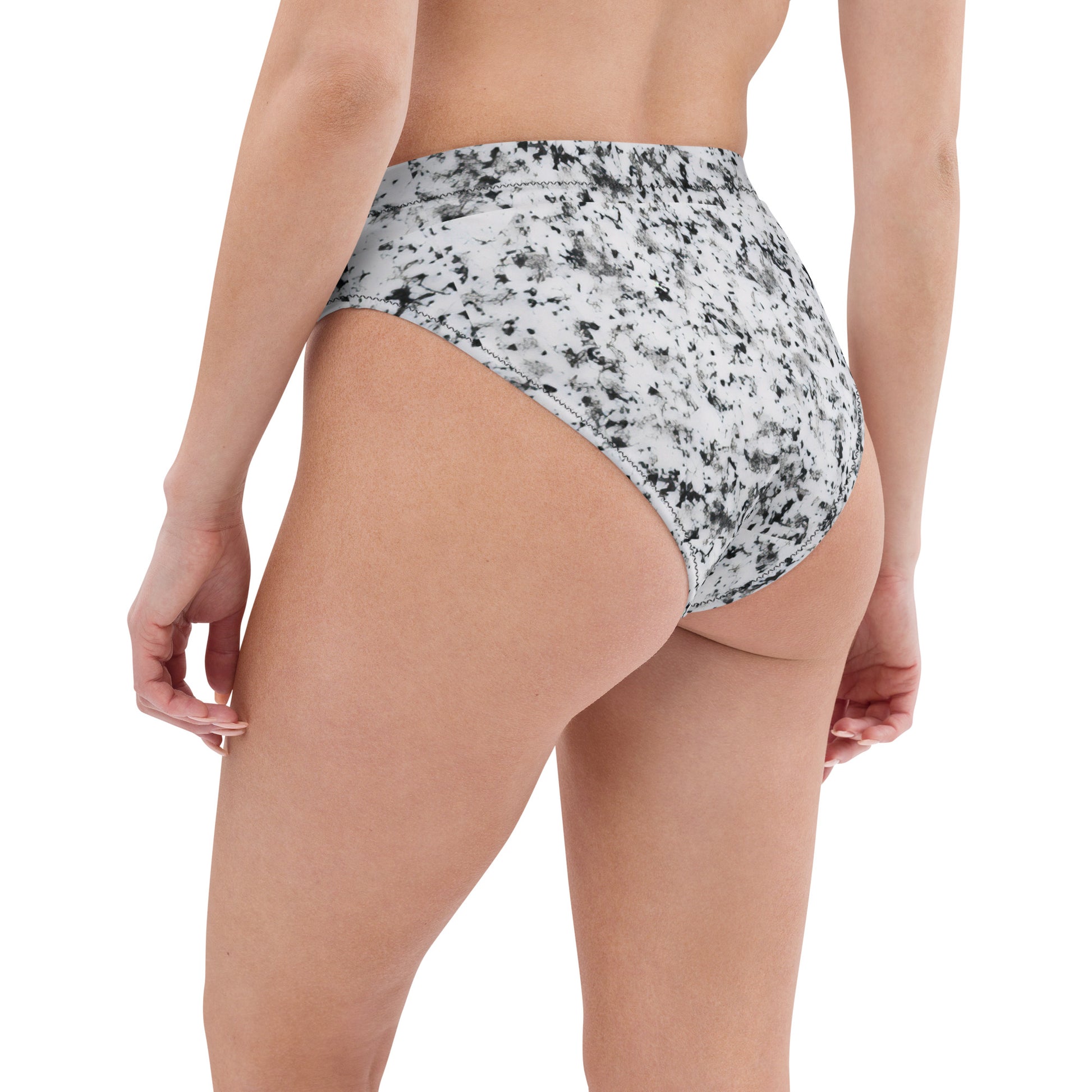 Rear view of woman wearing bikini bottom with pattern of black splotches set on a white background.