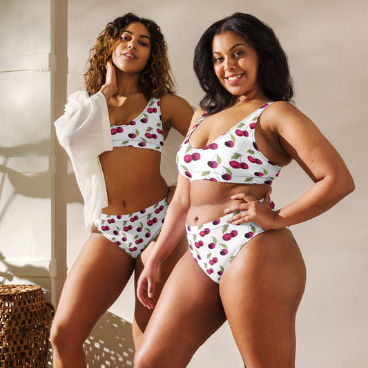 Two women, each wearing bikini with all-over cherry pattern set on a white background.
