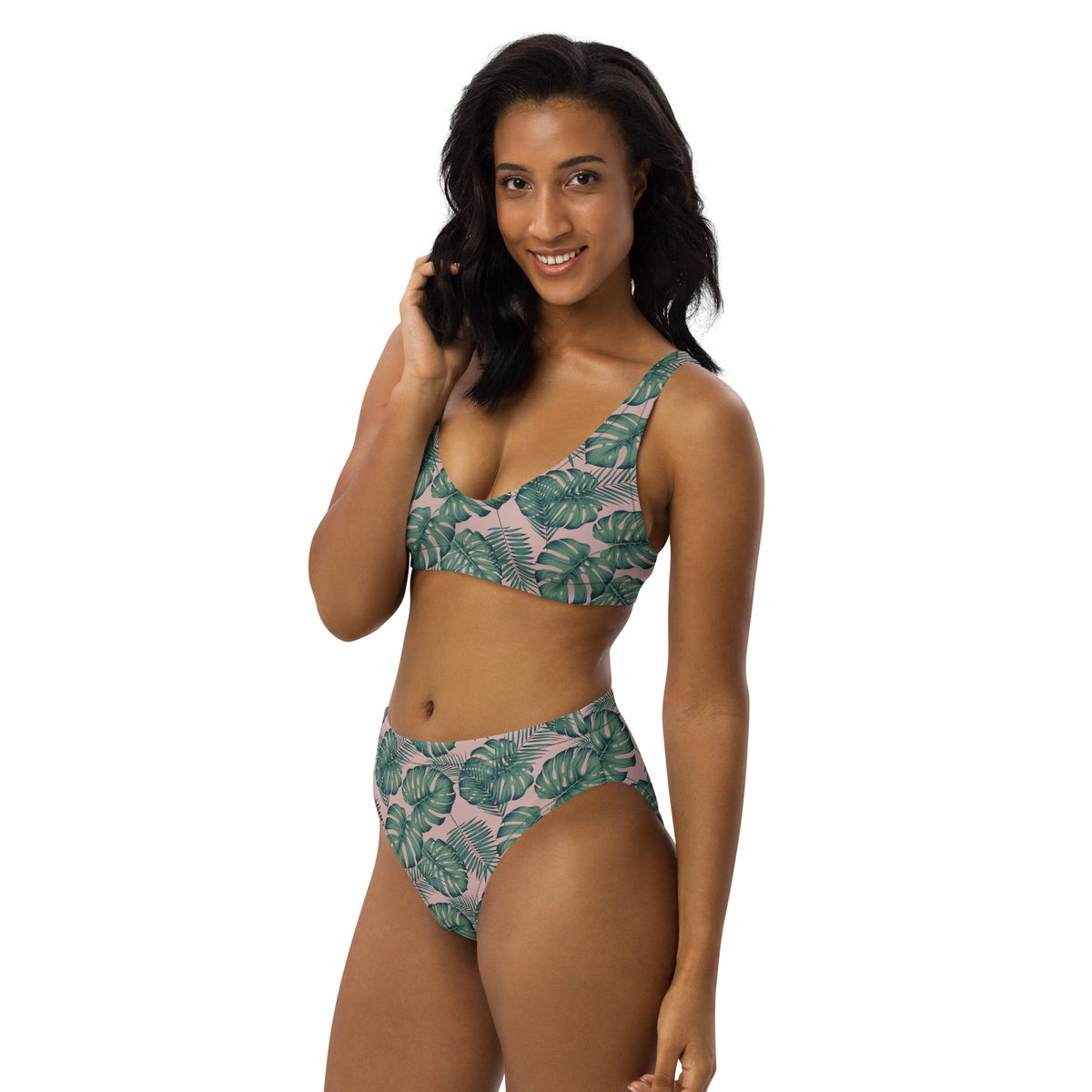 Woman wearing bikini with pattern of green palm leaves set on a pink background.