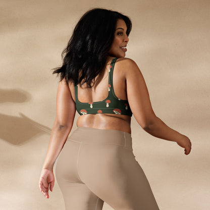 Rear view of woman wearing bikini top with pattern of mushrooms set on a green background.