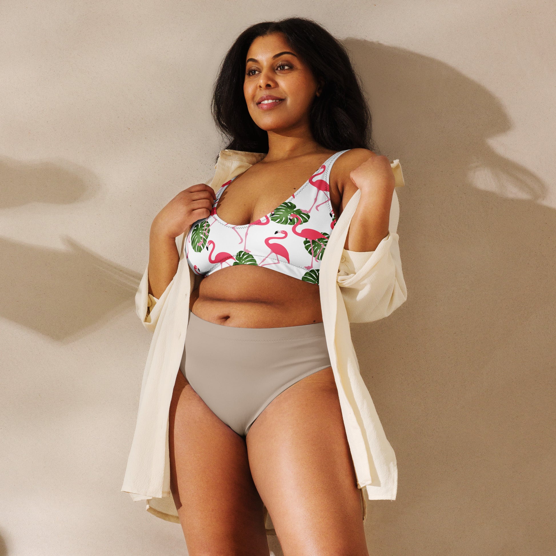 Woman wearing bikini top with all-over flamingo pattern set on white background.
