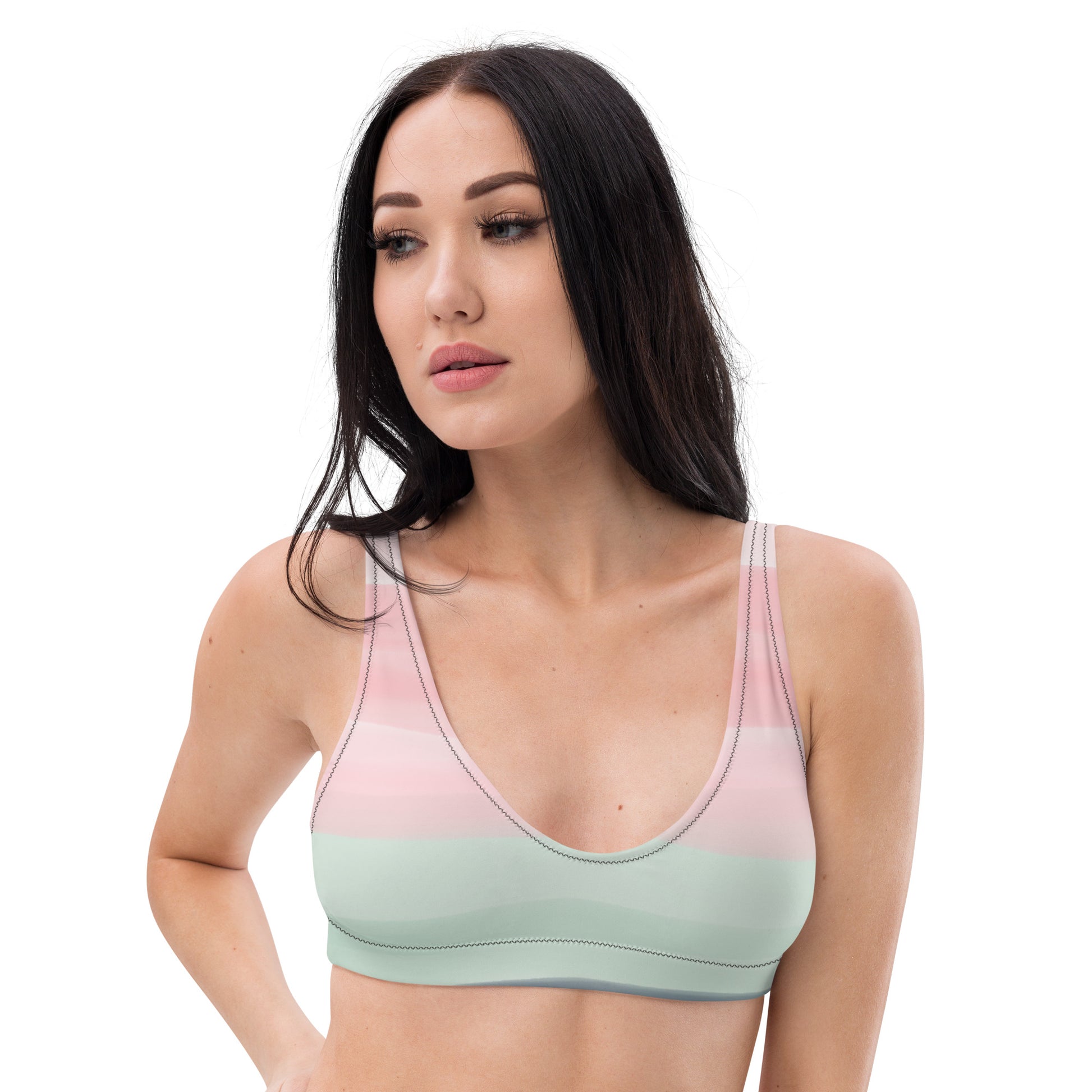 Woman wearing bikini top with design resembling watercolor. Dominant colors are pink and light green.