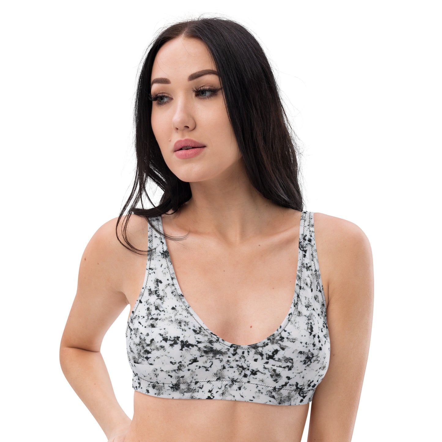 Woman wearing bikini top with pattern of black splotches set on a white background.