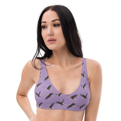 Woman wearing purple bikini top with pattern of bald eagles.