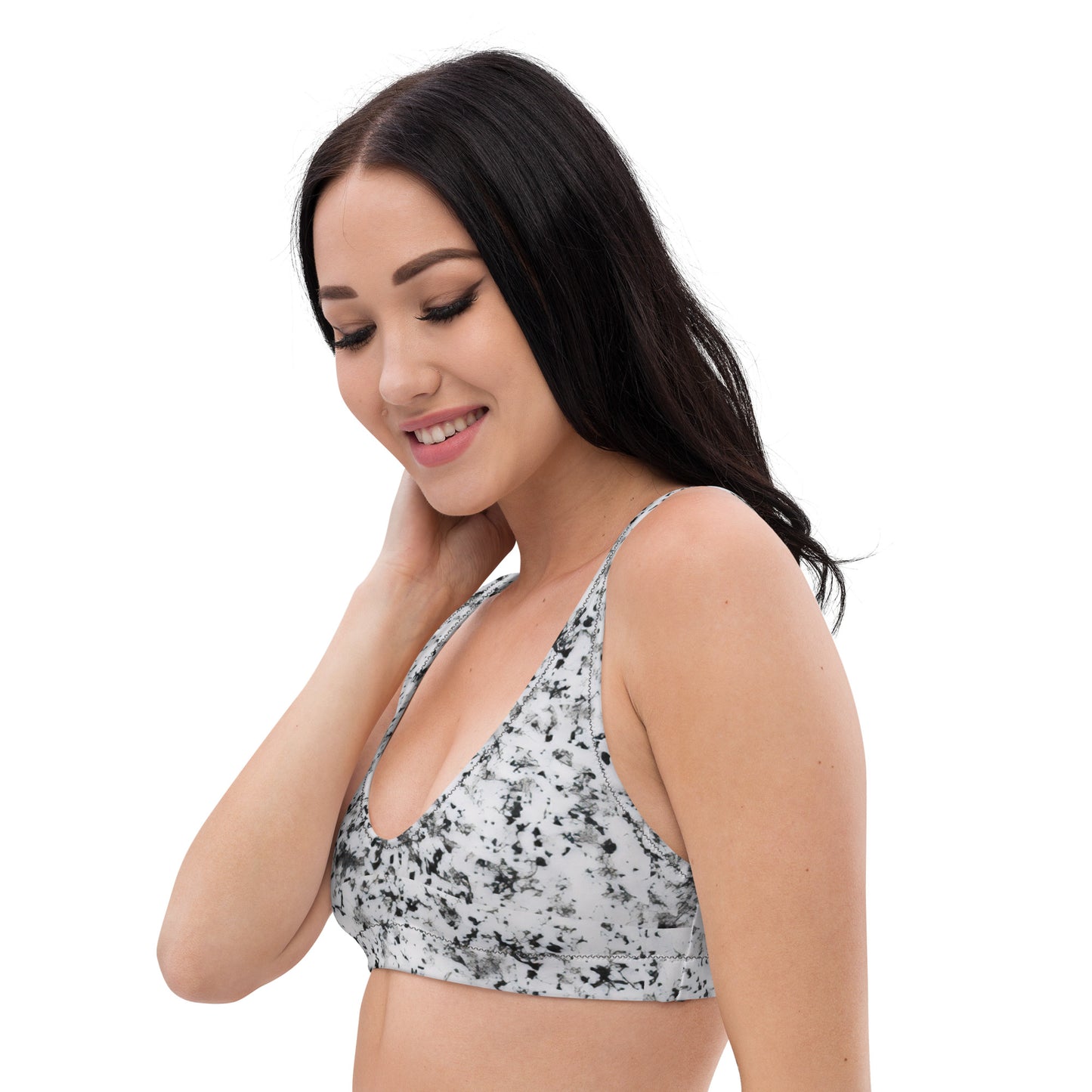 Woman wearing bikini top with pattern of black splotches set on a white background.