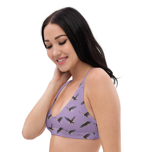 Woman wearing purple bikini top with pattern of bald eagles.
