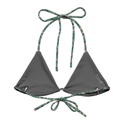 Back of bikini top with pattern of green palm leaves set on a pink background. Interior is gray.