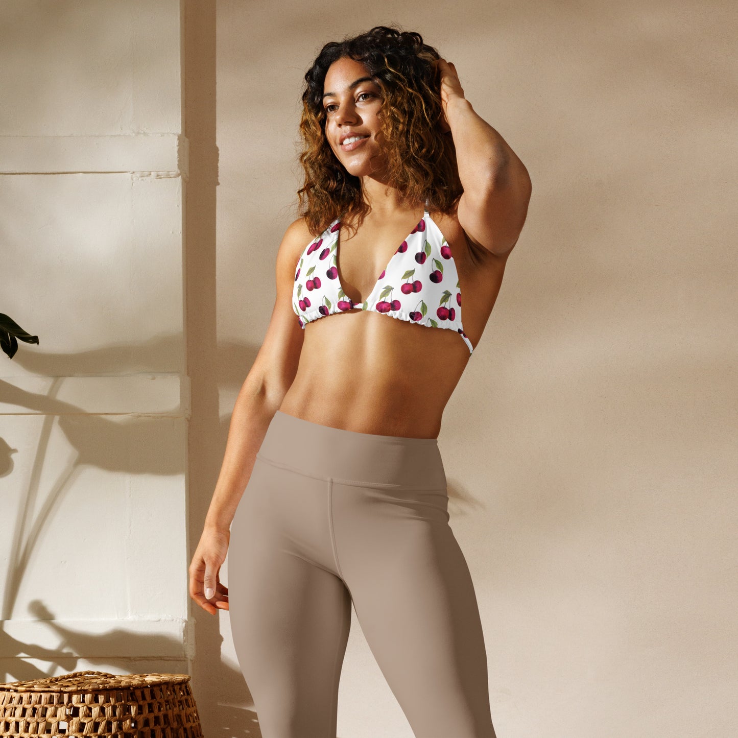 Woman wearing bikini top with all-over pattern of cherries set on a white background.
