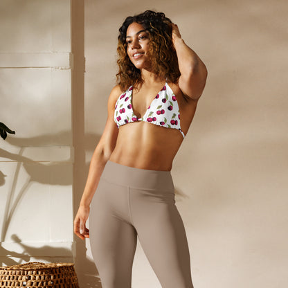 Woman wearing bikini top with all-over pattern of cherries set on a white background.