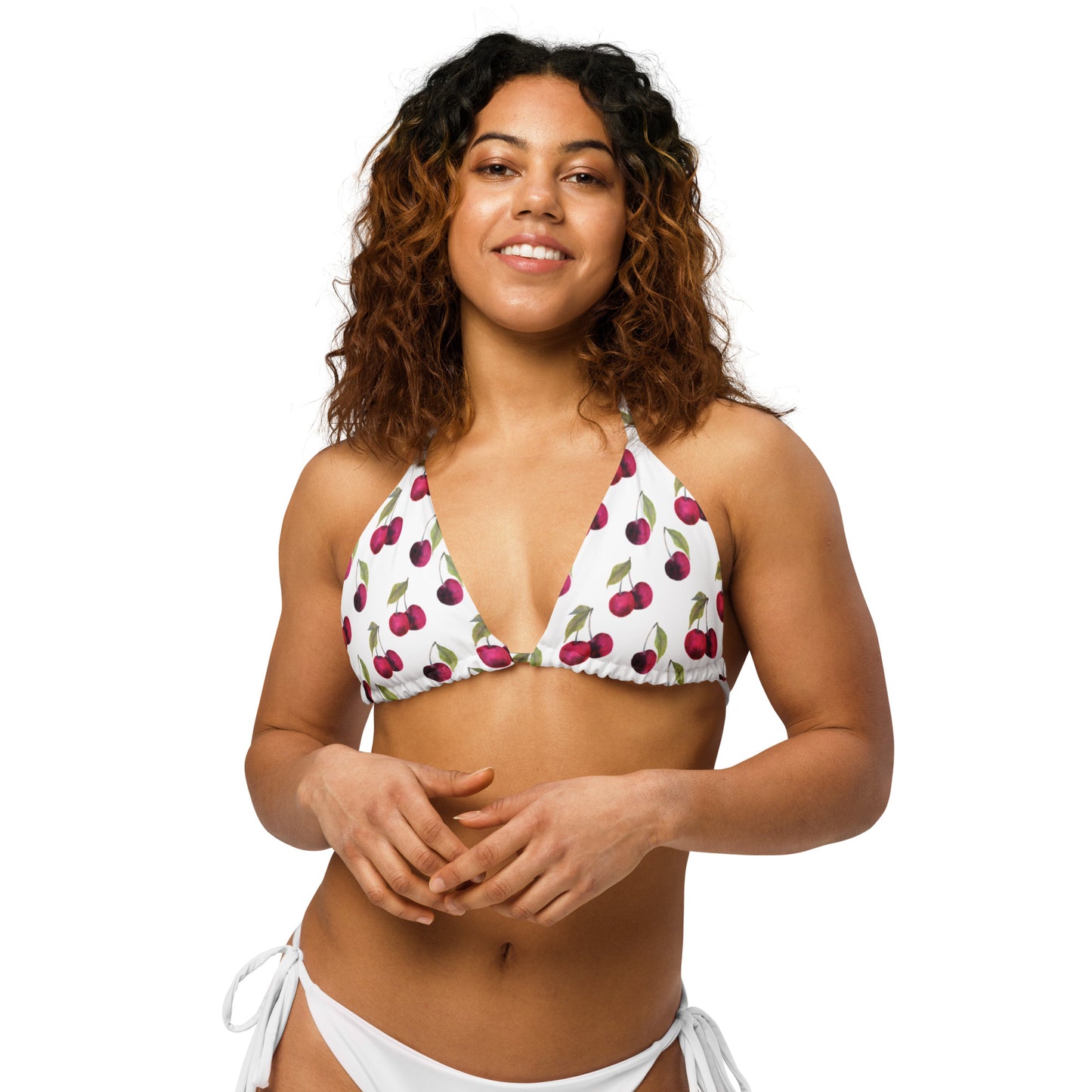 Woman wearing bikini top with all-over pattern of cherries set on a white background.