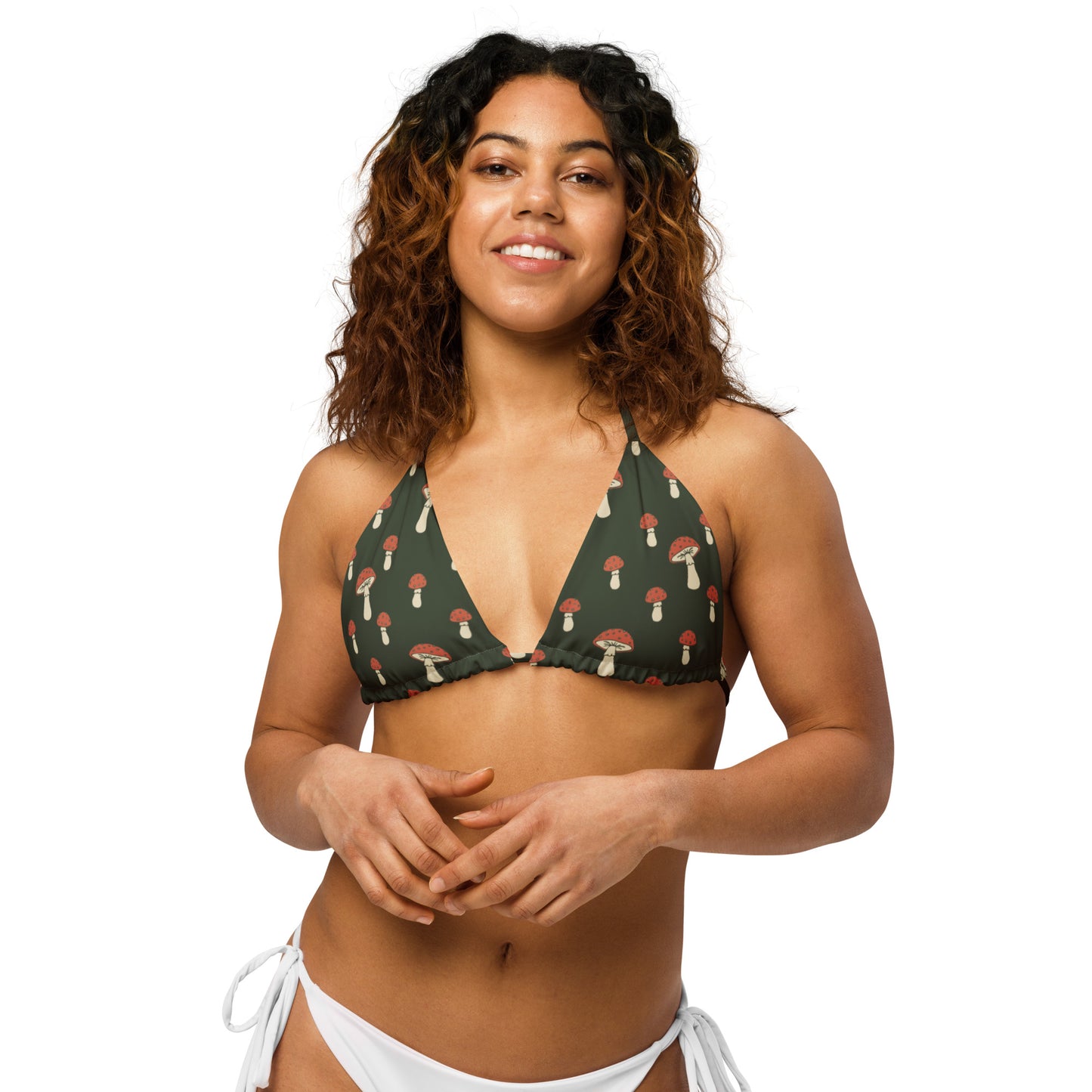Woman wearing bikini top with pattern of mushrooms set on a forest-green background.