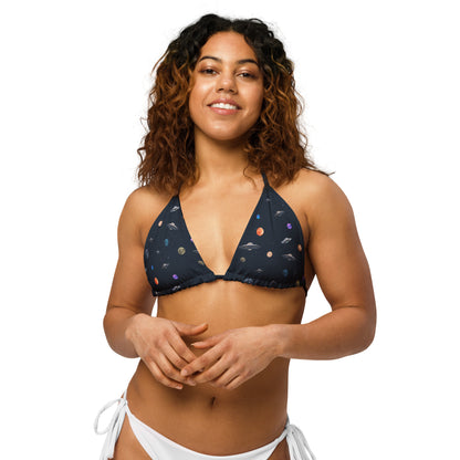 Woman wearing string bikini top with pattern of UFOs and planets in space.