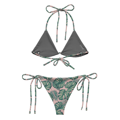 Back of bikini with pattern of green palm leaves set on a pink background. Interior is dark gray.