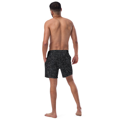 Rear view of man wearing swim trunks with black geometric pattern.