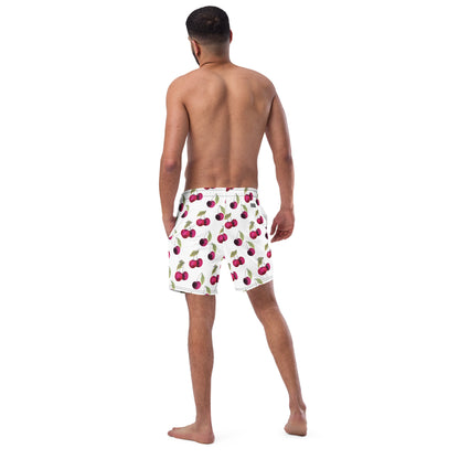 Rear view of man wearing swim trunks with pattern of cherries set on a white background.