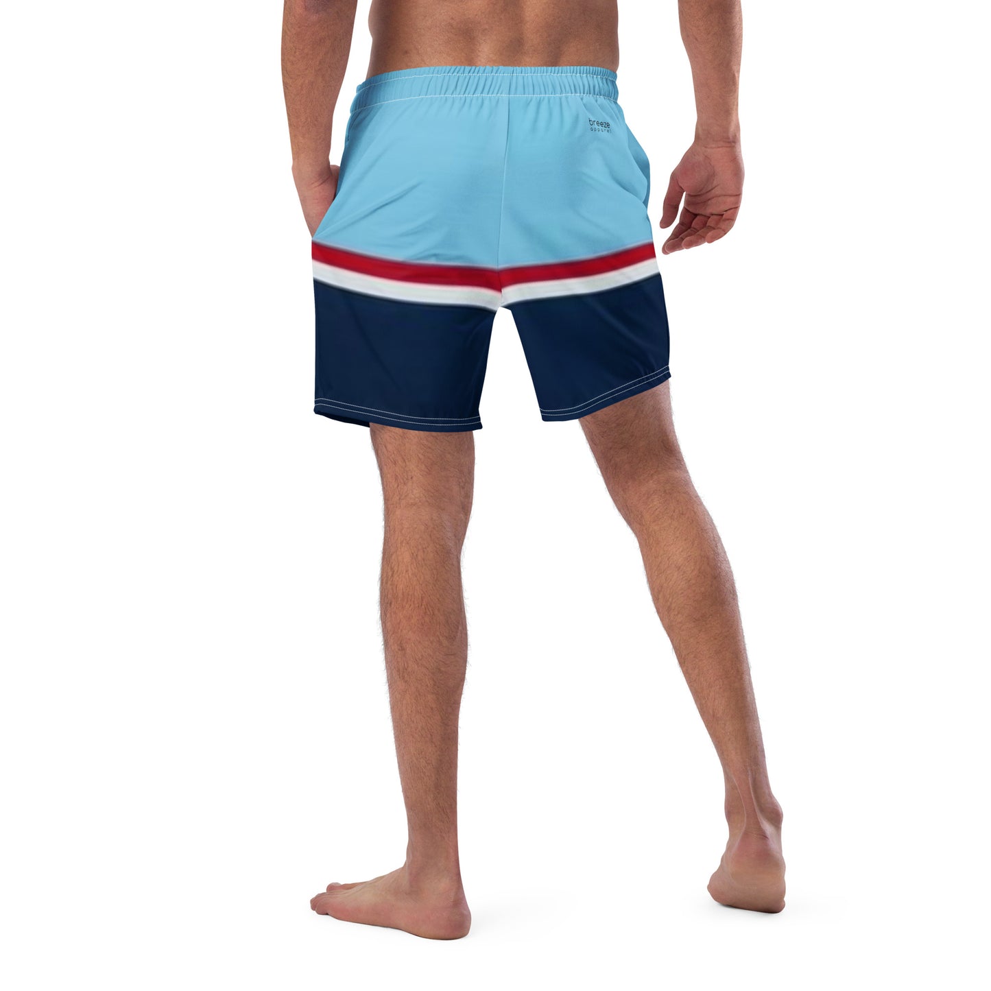 Rear view of man wearing swim trunks with pattern of light-blue on top, followed by a thinner red and thinner white line, followed by navy.
