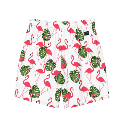 Swim trunks with pattern of pink flamingos and green leaves set on a white background.