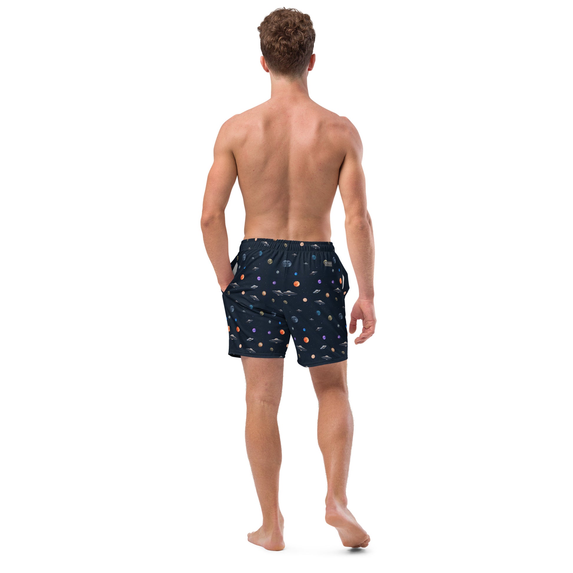 Man wearing swim trunks with graphic of planets and UFOs in space.
